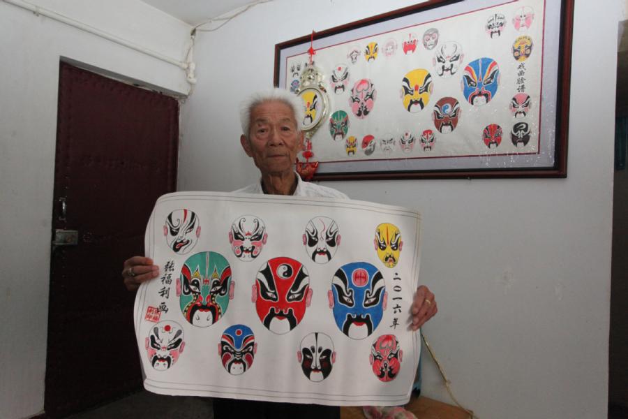 Zhang Fuli, 85, shows his painting works of Peking Opera facial masks.  (Photo//chinadaily.com.cn)