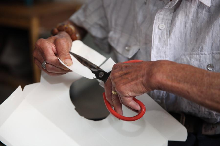 Zhang Fuli, 85, cuts the shape of a Peking Opera facial mask on a piece of paper. (Photo//chinadaily.com.cn)