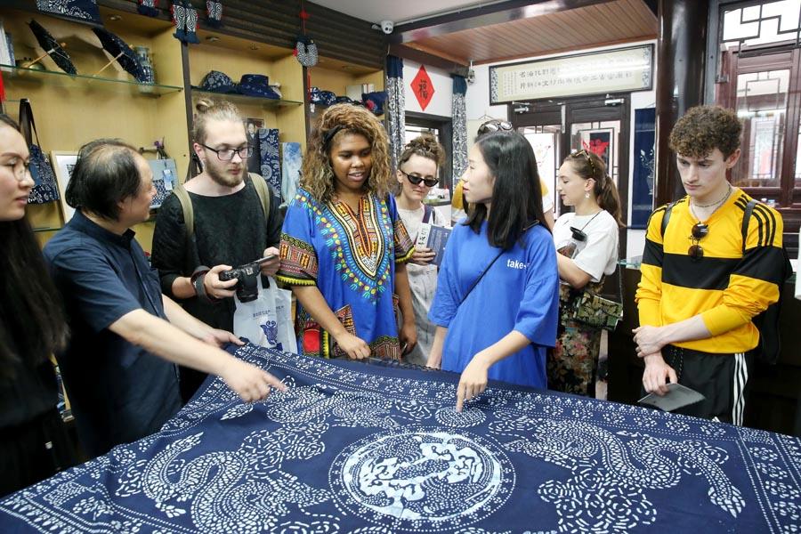 Chinese and British students from the China Academy of Art\'s creative fashion design camp listen to explanations of patterns on traditional Chinese blue calico in Nantong, East China\'s Jiangsu Province, on July 3, 2018. (Photo/Asianewsphoto)