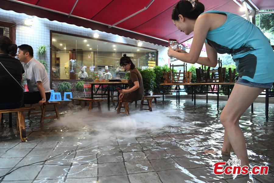 Diners enjoy hotpot while dipping their feet in a pool at a restaurant in Chongqing, July 5, 2018. Gold fish are kept in the pool, which allows customers to enjoy a footbath while eating the popular stew, a hot meal mixed with meat and vegetables. (Photo: China News Service/Chen Chao)