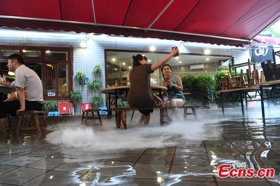 Diners enjoy hotpot while dipping their feet in a pool at a restaurant in Chongqing, July 5, 2018. Gold fish are kept in the pool, which allows customers to enjoy a footbath while eating the popular stew, a hot meal mixed with meat and vegetables. (Photo: China News Service/Chen Chao)