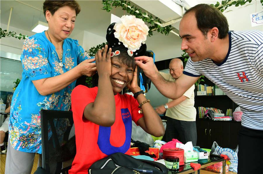 A teacher applies facial makeup to a foreign student in Zhenjiang city, Jiangsu Province, on July 9, 2018. (Photo/Asianewsphoto)