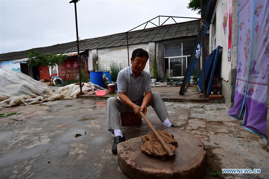 Local handicraftsman Ren Guohe prepares materials for making clay statuettes in Jinzhuang Village of Huaiyang County, central China\'s Henan Province, July 9, 2018. Originated from ancient sacrificial ceremonies, the hand-made clay statuette \