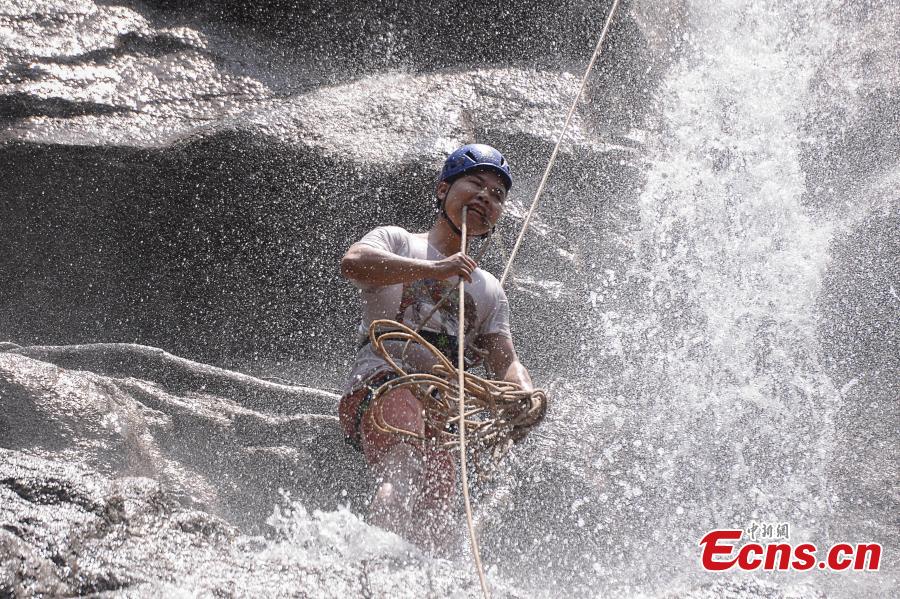 Sun Si abseils down a 106-meter-high waterfall in Jiulong River National Park in Rucheng County, Central China’s Hunan Province, July 10, 2018. Two participants took five minutes to descend a rope from a glass walkway at the top of a cliff to the ground below. (Photo: China News Service/Yang Huafeng)