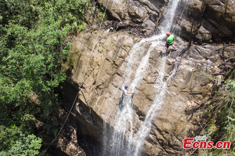 Two adventurers abseil down a 106-meter-high waterfall in Jiulong River National Park in Rucheng County, Central China’s Hunan Province, July 10, 2018. Two participants took five minutes to descend a rope from a glass walkway at the top of a cliff to the ground below. (Photo: China News Service/Yang Huafeng)