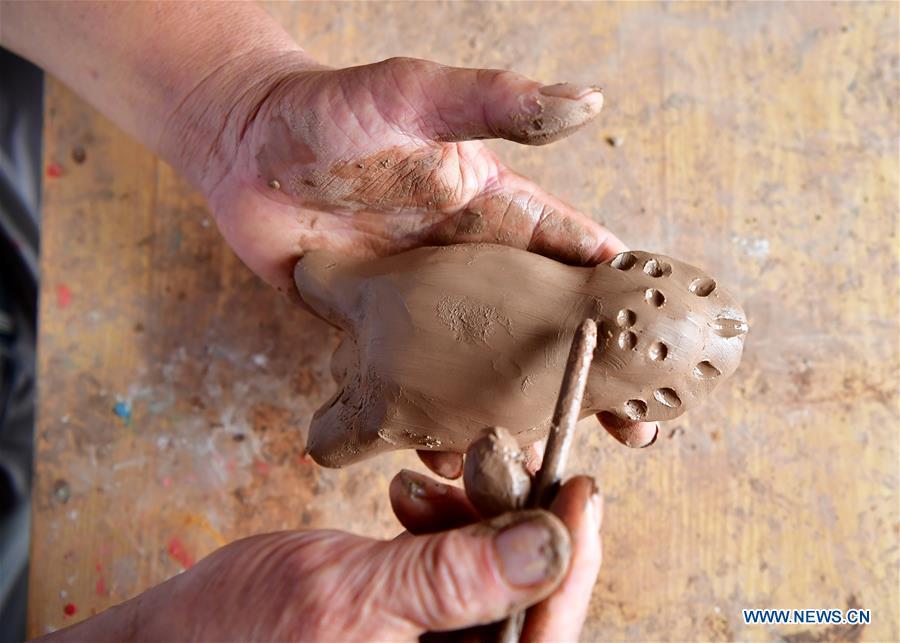 Local handicraftsman Ren Guohe makes a clay statuette in Jinzhuang Village of Huaiyang County, central China\'s Henan Province, July 9, 2018. Originated from ancient sacrificial ceremonies, the hand-made clay statuette \