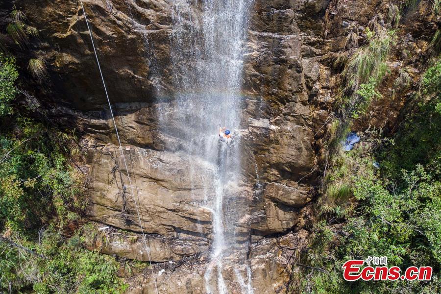 Two adventurers abseil down a 106-meter-high waterfall in Jiulong River National Park in Rucheng County, Central China’s Hunan Province, July 10, 2018. Two participants took five minutes to descend a rope from a glass walkway at the top of a cliff to the ground below. (Photo: China News Service/Yang Huafeng)