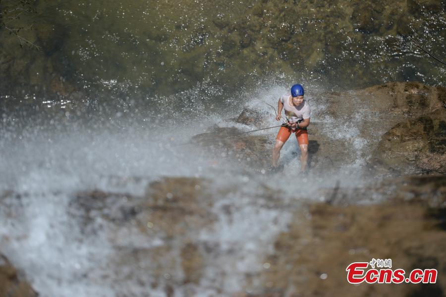 Sun Si abseils down a 106-meter-high waterfall in Jiulong River National Park in Rucheng County, Central China’s Hunan Province, July 10, 2018. Two participants took five minutes to descend a rope from a glass walkway at the top of a cliff to the ground below. (Photo: China News Service/Yang Huafeng)