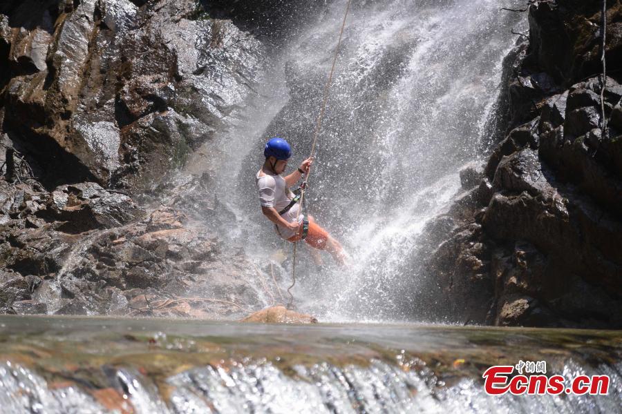 Sun Si abseils down a 106-meter-high waterfall in Jiulong River National Park in Rucheng County, Central China’s Hunan Province, July 10, 2018. Two participants took five minutes to descend a rope from a glass walkway at the top of a cliff to the ground below. (Photo: China News Service/Yang Huafeng)