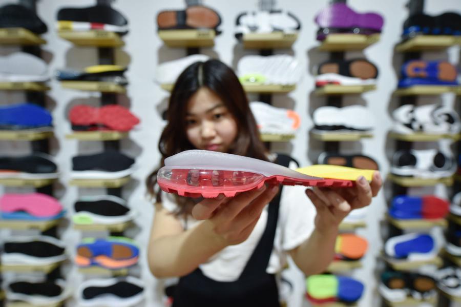 A saleswoman of a sole manufacturer displays an air-bag sole developed by the company in Jinjiang, Fujian Province, on April 20, 2017. (Photo/Xinhua)
Sound business ethics and credibility have fueled the prosperity of businesses in Jinjiang in Fujian Province. Hengan is among 46 listed privately owned enterprises and 822 companies with production value exceeding 100 million yuan ($15 million) in the city, which is about an hour\'s drive northeast of Xiamen.
Jinjiang has quickly grown from a cluster of fishing villages to become the most prosperous and developed county-level city in the province as well as a role model for other counties in the country. This has been accomplished thanks to thriving local private businesses predominantly based on manufacturing and trade.
Zhao Bei, an economics professor at Xiamen University, said the establishment of good credit and a solid reputation by Jinjiang\'s local business communities has kept the small and medium-sized private enterprises thriving. \