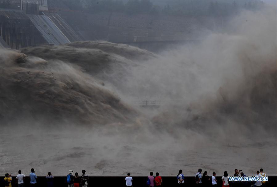 Tourists watch water gushing out from the Xiaolangdi Reservoir on the Yellow River in central China\'s Henan Province, July 11, 2018. (Xinhua/Li Jianan)