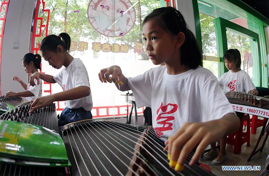Students learn playing zither during a class in Qinzhou City, south China\'s Guangxi Zhuang Autonomous Region, July 12, 2018. Students learn new skills during their summer vacation. (Xinhua/Zhang Ailin)