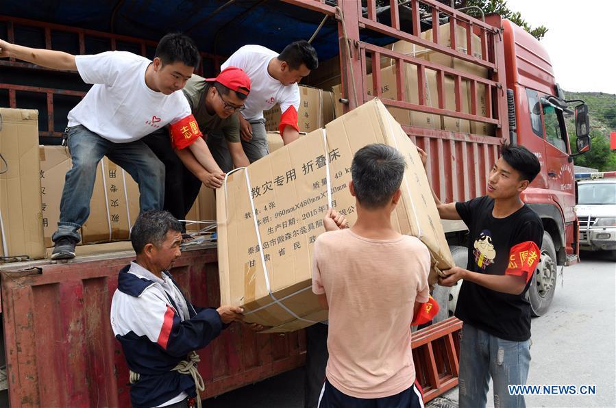 Villagers unload relief supplies for flood victims in Nanyu Town of Zhouqu County, northwest China\'s Gansu Province, July 15, 2018. Emergency relief supplies have been sent to severely flooded areas in Zhouqu County and rescue work has been carried out here. Heavy rainstorms triggered a landslide Thursday in Zhouqu County, but no casualties have been reported. (Xinhua/Fan Peishen)