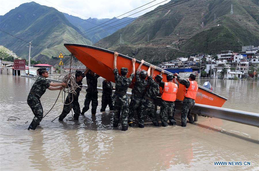 Soldiers carry a rescue boat in Nanyu Town of Zhouqu County, northwest China\'s Gansu Province, July 15, 2018. Emergency relief supplies have been sent to severely flooded areas in Zhouqu County and rescue work has been carried out here. Heavy rainstorms triggered a landslide Thursday in Zhouqu County, but no casualties have been reported. (Xinhua/Fan Peishen)