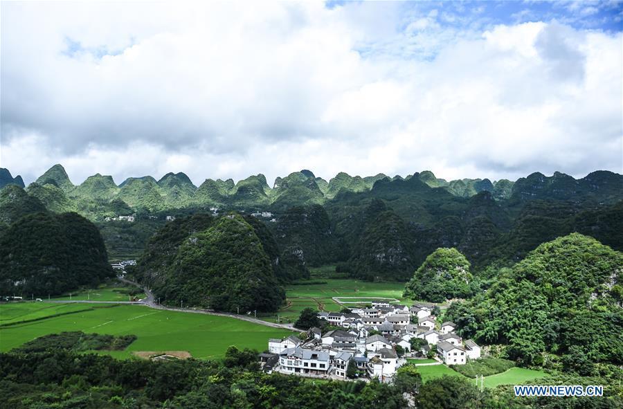 Photo taken on July 15, 2018 shows a village embraced by karst hills within the Wanfenglin scenic area in Xingyi, southwest China\'s Guizhou Province. (Xinhua/Tao Liang)