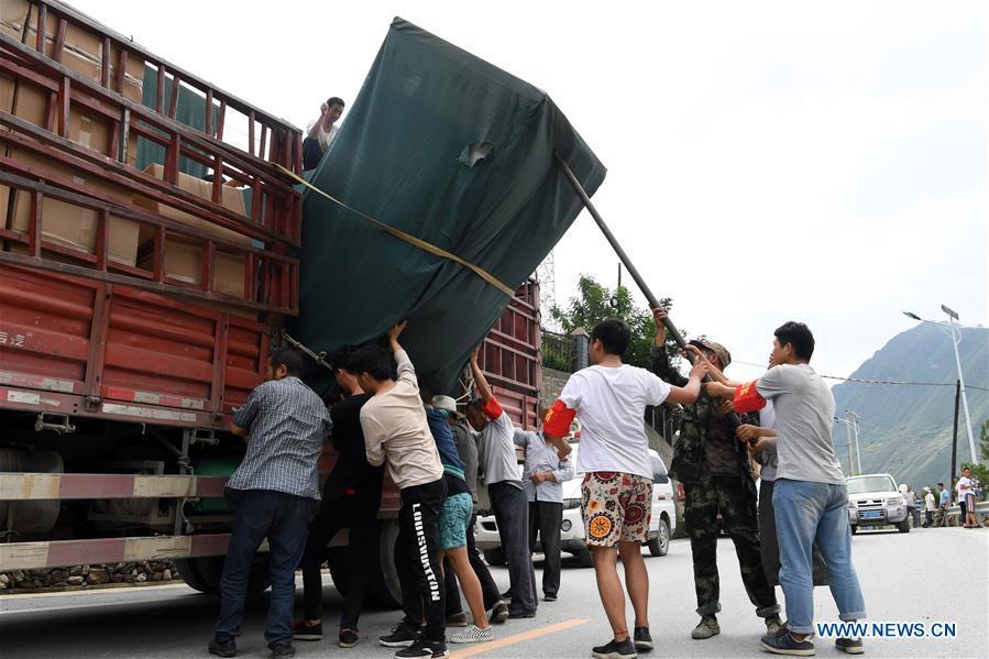 Villagers unload relief supplies for flood victims in Nanyu Town of Zhouqu County, northwest China\'s Gansu Province, July 15, 2018. Emergency relief supplies have been sent to severely flooded areas in Zhouqu County and rescue work has been carried out here. Heavy rainstorms triggered a landslide Thursday in Zhouqu County, but no casualties have been reported. (Xinhua/Fan Peishen)
