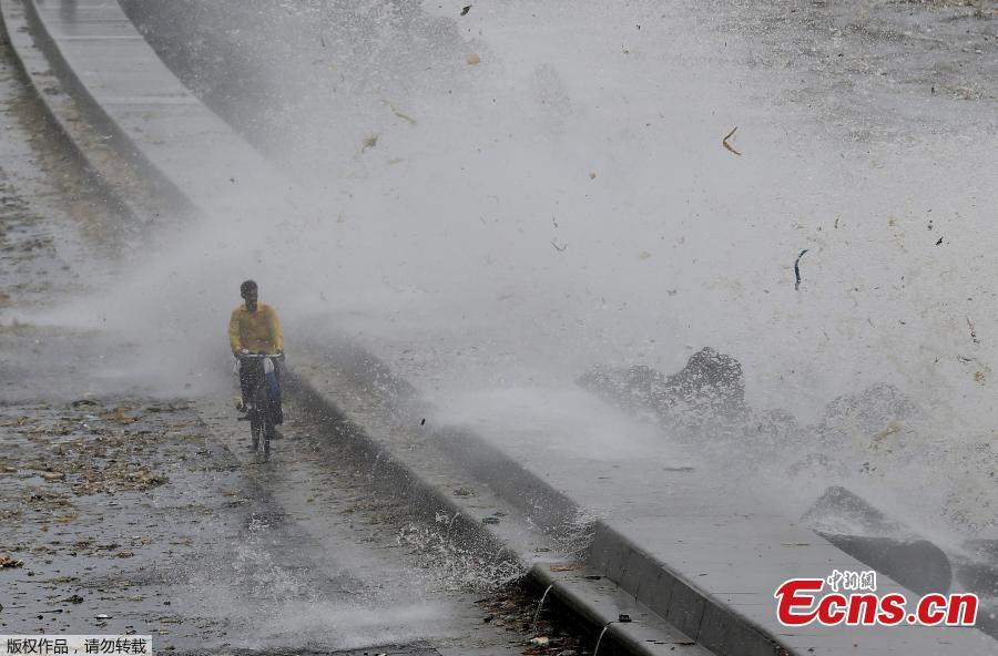 A man walks as a wave crashes during high tide at a sea front in Mumbai, India, July 13, 2018. (Photo/Agencies)