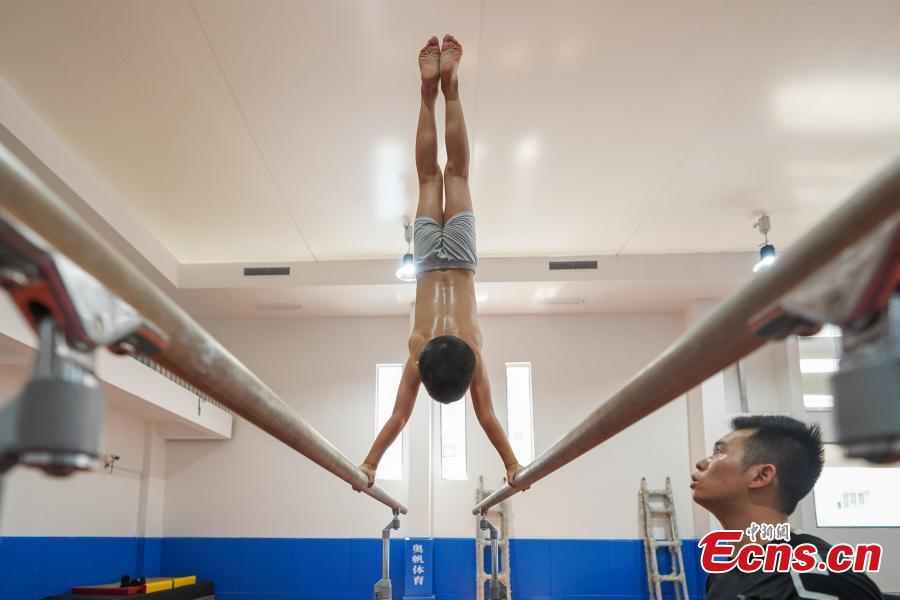 Instructor Liu Shiya trains student Ye Zhansong at the Amateur Children\'s Gymnastics Training School in Rongjiang County, Southwest China’s Guizhou Province, July 16, 2018. There are 60 children taking part in gymnastics training at the school during their spare time. Since 1972, the county has sent 21 athletes to the provincial gymnastics and gymnastics trampoline teams, among whom six later became national team members. The county is home to Liu Rongbing, who won a gold medal for the men\'s team in the 2014 World Artistic Gymnastics Championships. (Photo: China News Service/He Junyi)