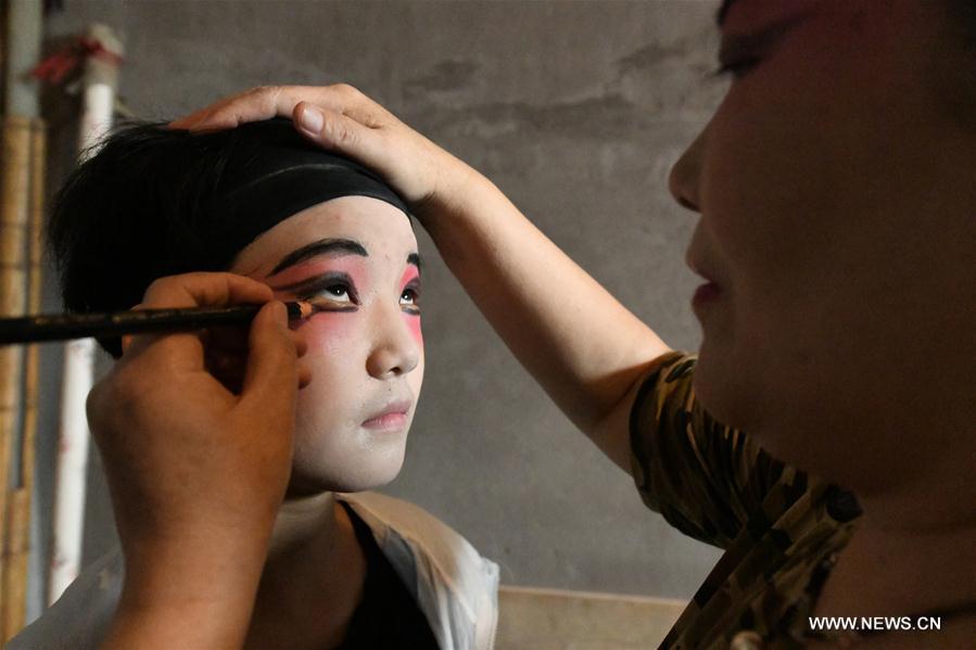 A teacher does facial make-up during an opera class for a student from a primary school in Shijiazhuang, north China\'s Hebei Province, July 18, 2018. Chinese students have entered their summer vacation, during which many of them chose to spend the vacation by developing their hobbies. (Xinhua/Chen Qibao)