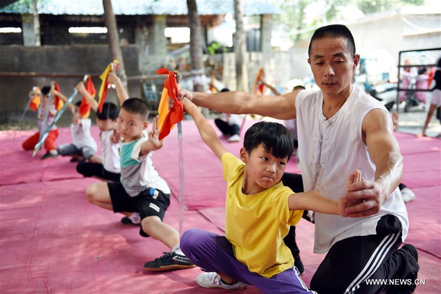 Students learn Chinese martial arts (Wushu) from the trainer Ma Kunpeng in Yancheng County of Linyi City, east China\'s Shandong Province, July 18, 2018. Chinese students have entered their summer vacation, during which many of them chose to spend the vacation by developing their hobbies. (Xinhua/Fang Dehua)