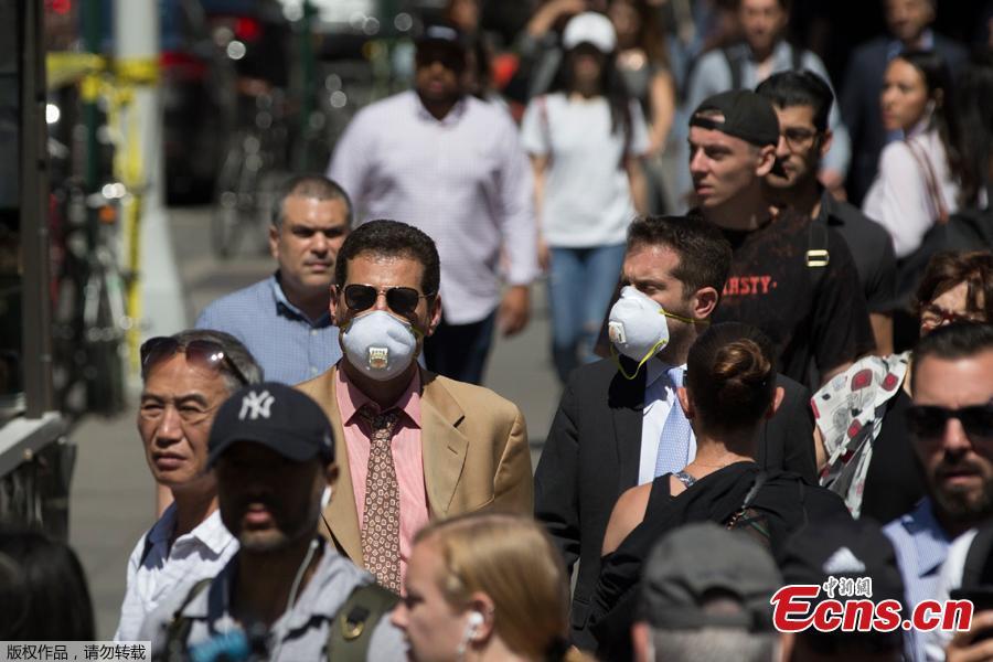 People wear masks after a steam pipe exploded at the Flatiron District in New York City, U.S., July 19, 2018. Five minor injuries have been reported, according to the New York City Fire Department. The incident prompted the evacuation of 28 buildings and warnings of possible asbestos risk. (Photo: China News Service/Liao Pan)