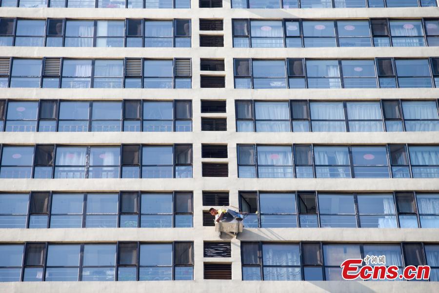 A man, attached to a rope, installs air-conditioning equipment on the outside of a tall building in Taiyuan City, North China’s Shanxi Province, July 20, 2018. (Photo: China News Service/Zhang Yun)