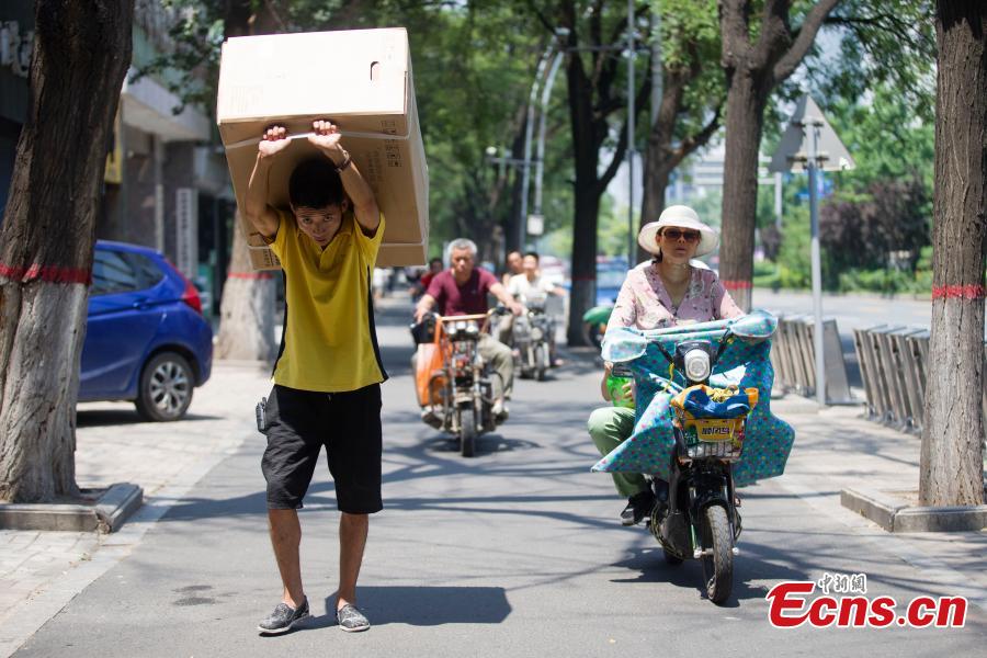 A man carries an air-conditioner in Taiyuan City, North China’s Shanxi Province, July 20, 2018. (Photo: China News Service/Zhang Yun)