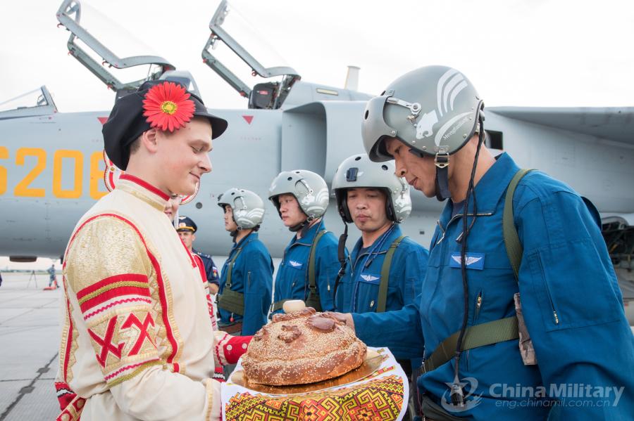 A Russian guy dressed in traditional clothing welcomes the Chinese pilots at the airport on July 20. All aircraft of the PLA Air Force to participate in the \
