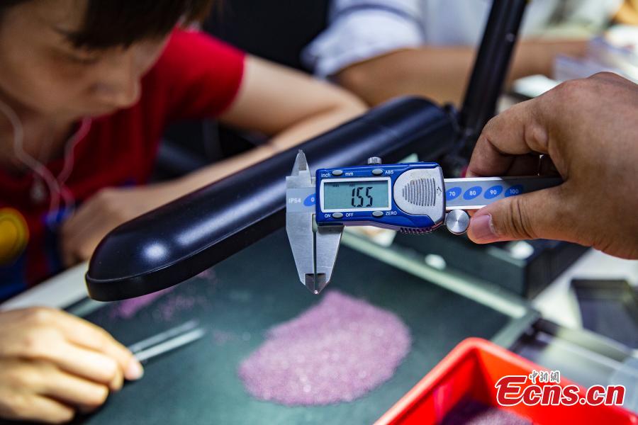 Staff members select gemstones in a jewelry store in Wuzhou City, South China’s Guangxi Zhuang Autonomous Region, July 24, 2018. They need to select at least 20,000 qualified pieces from more than 100,000 gemstones a day. Wuzhou is widely held to be the world capital for artificial gems and a trading center that now serves China and the rest of the world. Since the first factory was established there in 1982, Wuzhou now boasts an annual production value for the industry of approximately 3.2 billion yuan ($470 million). (Photo: China News Service/Chen Guanyan)