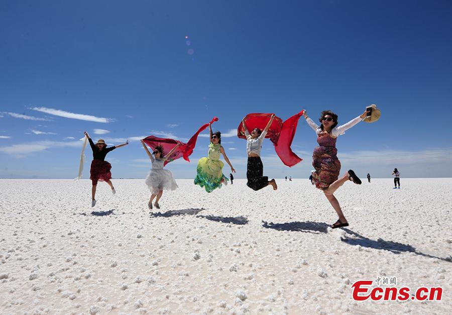 Tourists enjoy the scenery of the Qarhan salt lake in Golmud, Northwest China\'s Qinghai Province, July 25, 2018. The Qarhan salt lake, with a total area of 5,856 square kilometers, is the largest salt lake in China. The lake\'s abundant deposit of halide salts makes it a major mineral center. In the vast lake, the salt blossoms like flowers and takes the form of pillars, corals and pearls. (Photo: China News Service/Fu Yu).