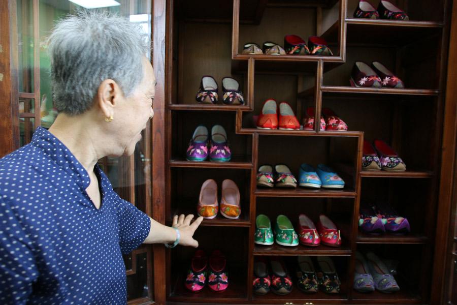 Wang Guanqin introduces her collection of handcrafted Chinese embroidered shoes to visitors in Beijing on July 21, 2018. (Photo/chinadaily.com.cn)
Ten enthusiasts of traditional Chinese embroidery worked under the wing of embroidered shoe-making master Wang Guanqin in Beijing on July 21.
As participants in the intangible cultural heritage experience program of Great Seed, a global community for enthusiasts of intangible cultural heritage, they learned about and experienced this heritage through close talks with inheritors or masters, and from hands-on experience.
During their talks with the 79-year-old master, who has been engaged in this craft most of her life, the participants were fascinated with the embroidered shoes. They tried to make the soles and uppers of the shoes themselves under her professional guidance, and learned about the cultural connotation and history of making embroidered shoes.