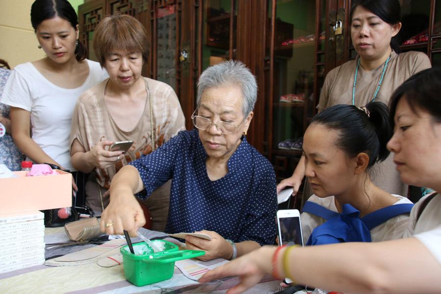 Wang Guanqin guides participants in Great Seed’s intangible cultural heritage experience program as they make shoes, July 21, 2018. (Photo/chinadaily.com.cn)