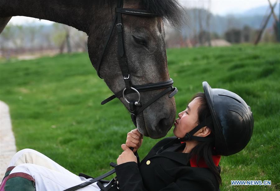 Tang Siqi, a student of Sunshine Riding School, kisses a horse during an outdoor training session in Yihuang County of Fuzhou, east China\'s Jiangxi Province, March 14, 2018. Equestrianism had never been heard of in Yihuang, an agricultural county in east China\'s Jiangxi Province, until Sunshine Riding School began recruiting rural teenagers in 2015. So far, most of the 90 students are working or aspiring to work in horse riding clubs in China\'s largest cities such as Beijing, Shanghai and Hangzhou. (Xinhua/Zhou Mi)