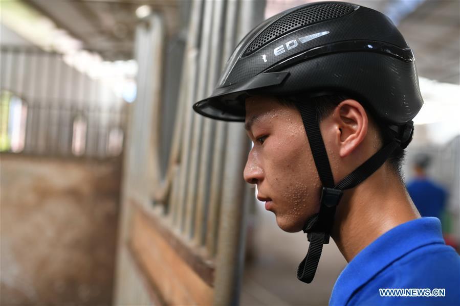 Huang Wanpeng, a student of Sunshine Riding School, works at the school stable in Yihuang County of Fuzhou, east China\'s Jiangxi Province, July 25, 2018. Equestrianism had never been heard of in Yihuang, an agricultural county in east China\'s Jiangxi Province, until Sunshine Riding School began recruiting rural teenagers in 2015. So far, most of the 90 students are working or aspiring to work in horse riding clubs in China\'s largest cities such as Beijing, Shanghai and Hangzhou. (Xinhua/Zhou Mi)
