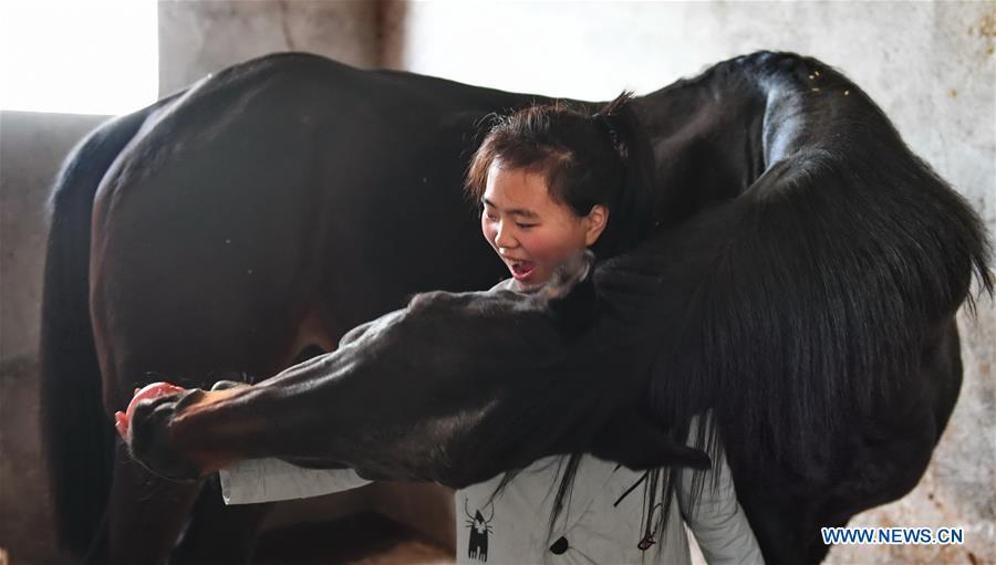 Tang Siqi, a student of Sunshine Riding School, feeds an apple to a horse in Yihuang County of Fuzhou, east China\'s Jiangxi Province, March 14, 2018. Equestrianism had never been heard of in Yihuang, an agricultural county in east China\'s Jiangxi Province, until Sunshine Riding School began recruiting rural teenagers in 2015. So far, most of the 90 students are working or aspiring to work in horse riding clubs in China\'s largest cities such as Beijing, Shanghai and Hangzhou. (Xinhua/Zhou Mi)
