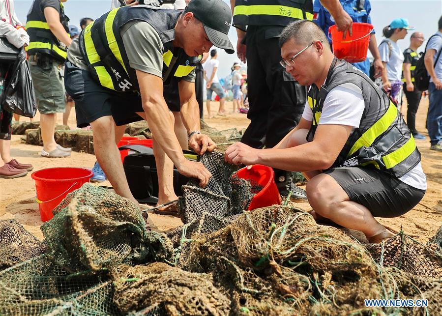Volunteers clean up trash on a beach during an event calling for attention to marine ecology protection at the Golden Dream Bay in Qinhuangdao, north China\'s Hebei Province, July 27, 2018. (Xinhua/Cao Jianxiong)