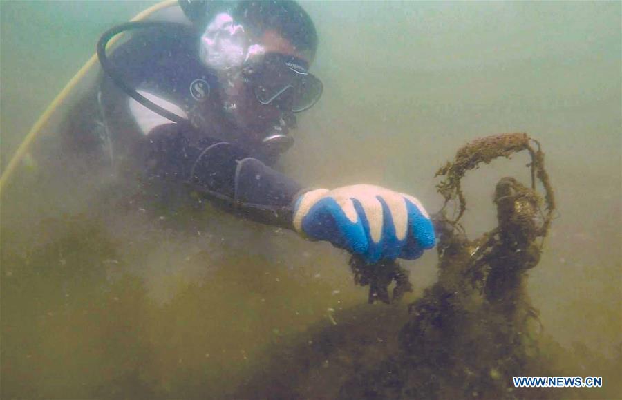 A volunteer cleans up marine trash during an event calling for attention to marine ecology protection at the Golden Dream Bay in Qinhuangdao, north China\'s Hebei Province, July 27, 2018. (Xinhua/Cao Jianxiong)