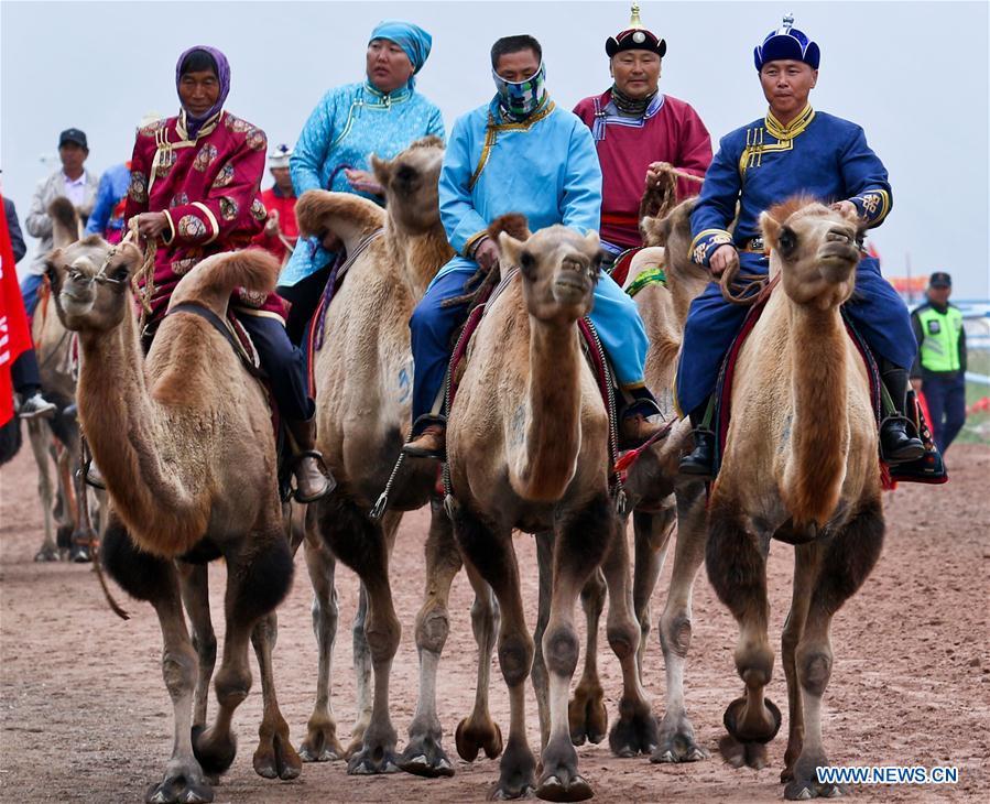 People are to take part in a camel racing during a traditional ethnic minorities sports meeting held at a racecourse in Sunan Yugur Autonomous County, northwest China\'s Gansu Province, July 28, 2018. (Xinhua/Wang Jiang)