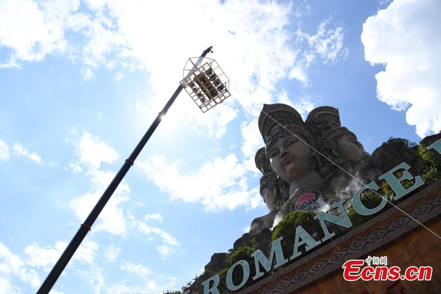 Participants face the challenge of eating rice noodles in a transparent room, hoisted 50 meters off the ground, near a giant statue at a scenic spot in Guilin City, South China’s Guangxi Zhuang Autonomous Region, July 29, 2018. Scared of the height, the participants gave up on the dare when the room was just ten meters off the ground. (Photo: China News Service/Chen Chen)