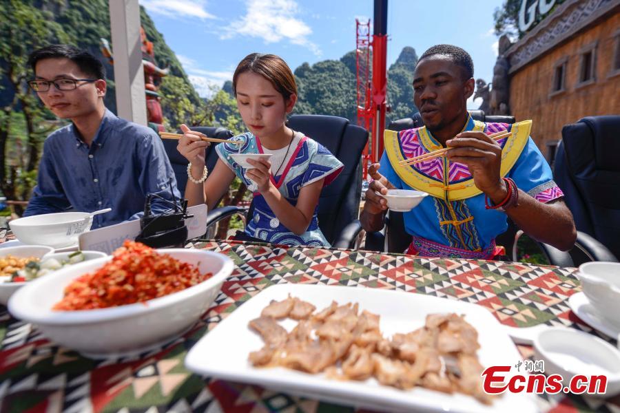 Participants face the challenge of eating rice noodles in a transparent room, hoisted 50 meters off the ground, near a giant statue at a scenic spot in Guilin City, South China’s Guangxi Zhuang Autonomous Region, July 29, 2018. Scared of the height, the participants gave up on the dare when the room was just ten meters off the ground. (Photo: China News Service/Chen Chen)