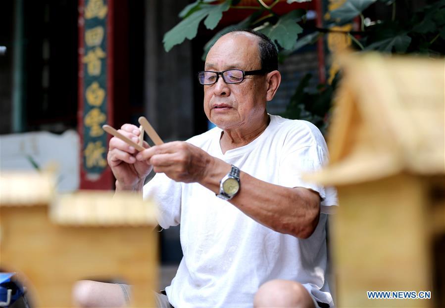 Zhang Xiaocheng makes a model using discarded wooden sticks in Chengguan Town of Wu\'an City, north China\'s Hebei Province, July 31, 2018. 70-year-old Zhang has made over 60 handicrafts using discarded wooden sticks. (Xinhua/Wang Xiao)