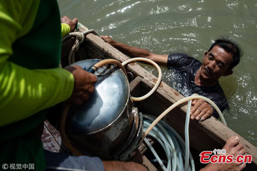 This photo taken on June 12, 2018 shows Bhoomin Samang emerging from a dive into Bangkok\'s Chao Phraya river to hunt for sunken treasure. There is a small community in Thailand known as \'Indiana Jones\' divers, who brave the inky-black underworld of the trash-filled waterway in search of coins, china, jewelry and scrap metal.(Photo/VCG)
