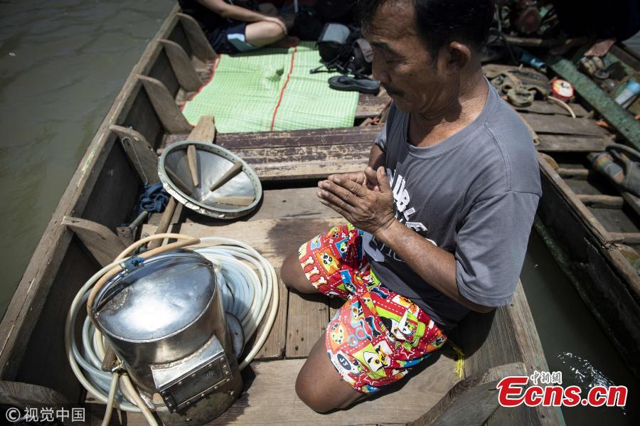 This picture taken on June 12, 2018 shows diver Bhoomin Samang praying in front of his homemade metal scuba helmet before he dives to the bottom of the Bangkok\'s Chao Phraya river to search for valuables. There is a small community in Thailand known as \'Indiana Jones\' divers, who brave the inky-black underworld of the trash-filled waterway in search of coins, china, jewelry and scrap metal. (Photo/VCG)