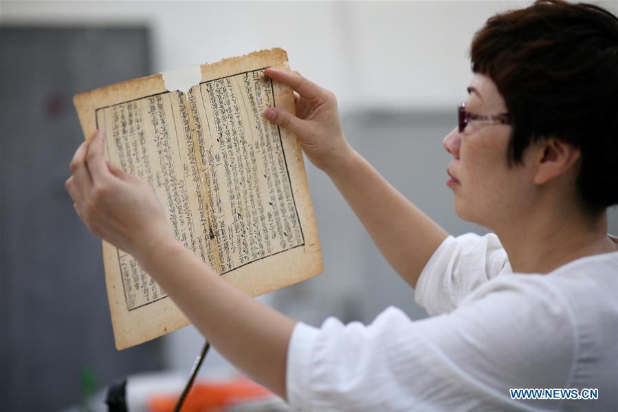 Gao Huiyun checks an ancient book at a workshop in Shijiazhuang, capital of north China\'s Hebei Province, Aug. 2, 2018. Gao Huiyun is a teacher of cultural relics restoration and protection at Hebei Vocational Art College. Gao has restored over 1,000 ancient books in her 13-year career time. (Xinhua/Chen Qibao)