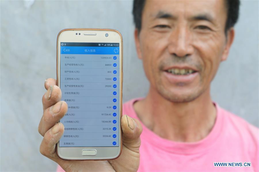Wang Qingyou shows his family income using a mobile phone app in Guiyang, capital of southwest China\'s Guizhou Province, July 14, 2018. Guizhou has become a pioneer in China\'s big data development. Big data is being widely applied in government management, business and daily life, contributing over 20 percent to the economic growth of Guizhou Province. The number of big data-related companies in Guizhou Province has grown from less than 1,000 in 2013 to more than 8,500 in 2018.(Xinhua/Ou Dongqu)