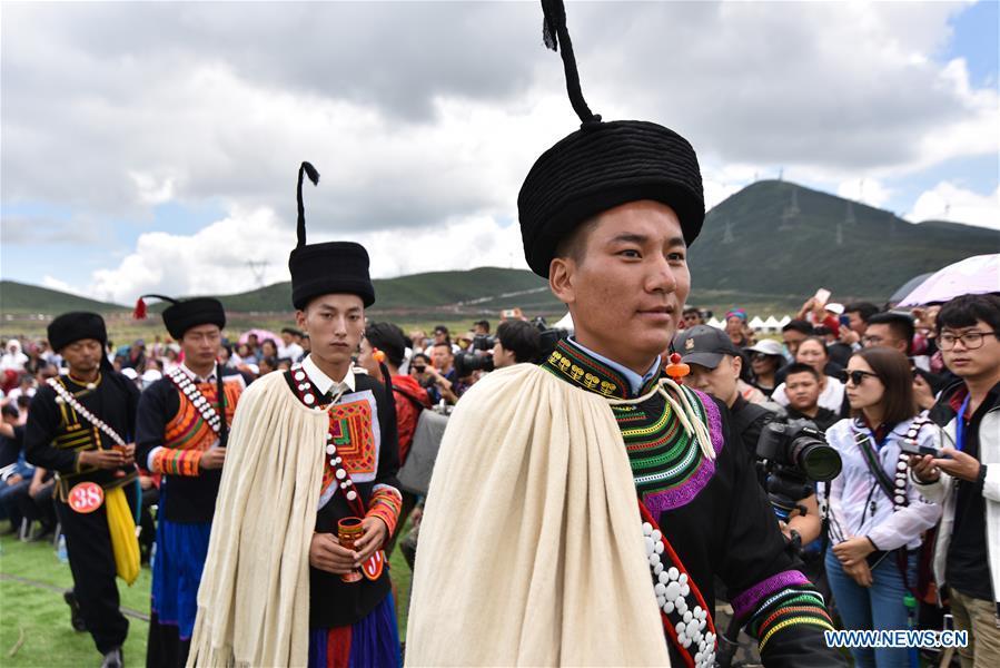 Contestants offer local wine for guests during a beauty contest of the torch festival of Yi ethnic group on a grassland in Zhaojue County, southwest China\'s Sichuan Province, Aug. 6, 2018. (Xinhua/Lyu Mingze)