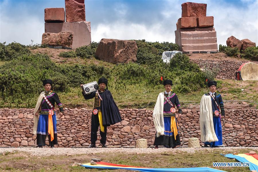 A contestant offers local food for guests during a beauty contest of the torch festival of Yi ethnic group on a grassland in Zhaojue County, southwest China\'s Sichuan Province, Aug. 6, 2018. (Xinhua/Lyu Mingze)