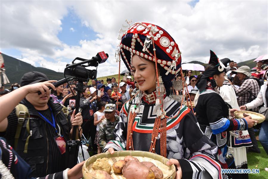 A contestant offers local food for guests during a beauty contest of the torch festival of Yi ethnic group on a grassland in Zhaojue County, southwest China\'s Sichuan Province, Aug. 6, 2018. (Xinhua/Lyu Mingze)