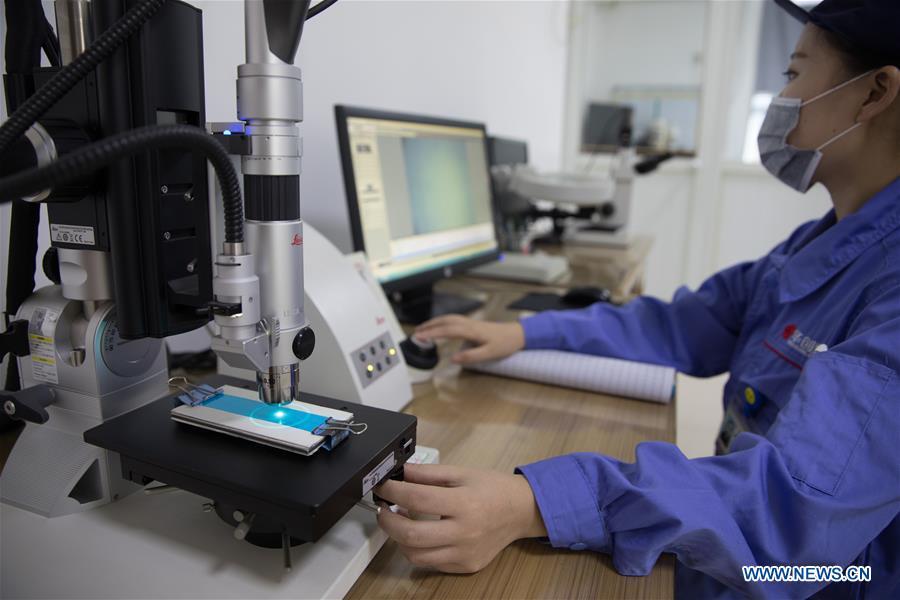 A staff member checks a piece of copper foil product for making lithium battery at Huachuang New Material Co., Ltd in Tongling City, east China\'s Anhui Province, Aug. 8, 2018. Tongling government takes measures to improve ecological environment and develop green industry along the Yangtze River. (Xinhua/Jin Liwang)