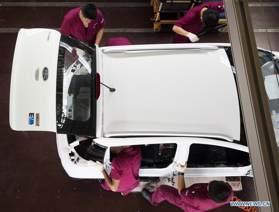 Staff members work on a new energy vehicle at a JAC Motors factory in Tongling City, east China\'s Anhui Province, Aug. 7, 2018. Tongling government takes measures to improve ecological environment and develop green industry along the Yangtze River. (Xinhua/Jin Liwang)